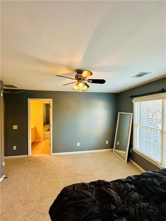 bedroom featuring ceiling fan, connected bathroom, and light carpet