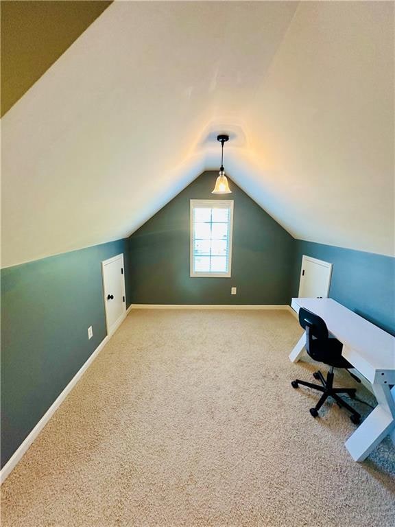 unfurnished office featuring carpet floors and lofted ceiling