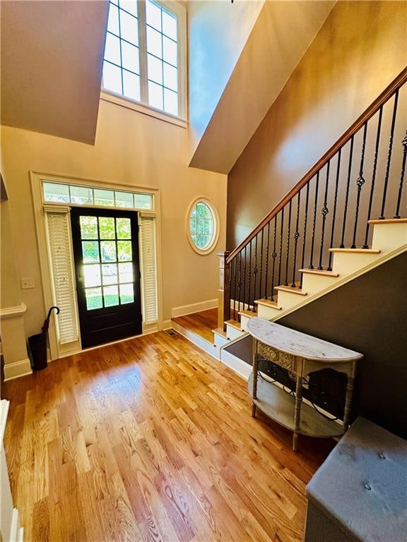 foyer with hardwood / wood-style floors and a towering ceiling