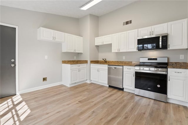 kitchen featuring visible vents, light wood-style flooring, white cabinetry, and stainless steel appliances