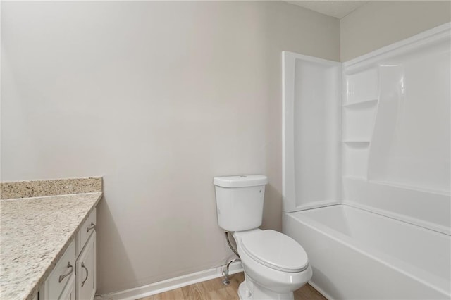 bathroom featuring toilet, shower / washtub combination, wood finished floors, baseboards, and vanity