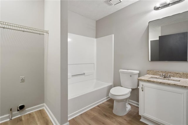 full bathroom with a textured ceiling, toilet, vanity, and wood finished floors