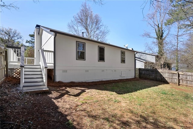 back of property with fence, stairway, a deck, a yard, and crawl space