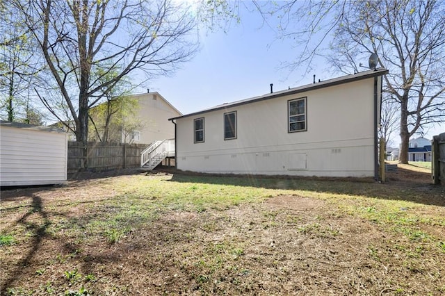 rear view of property with fence, a lawn, an outdoor structure, crawl space, and a storage unit