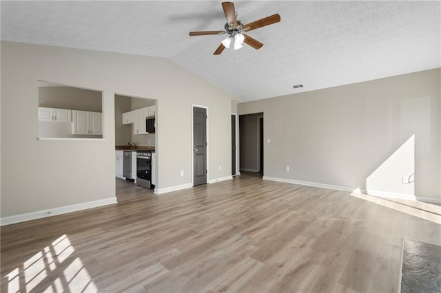 unfurnished living room featuring a textured ceiling, light wood-style flooring, a ceiling fan, and vaulted ceiling