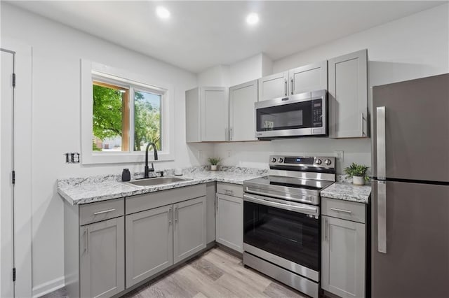 2060 Panstone Ct SW, Marietta, GA 30060 - kitchen featuring appliances with stainless steel finishes, gray cabinetry, a sink, light wood-style flooring, and light stone counters