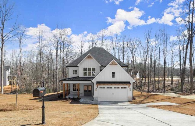 modern farmhouse with a front yard, covered porch, and a garage