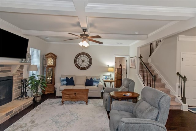 living room with beamed ceiling, coffered ceiling, ceiling fan, crown molding, and a brick fireplace