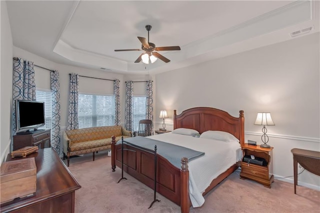 carpeted bedroom featuring ceiling fan and a tray ceiling