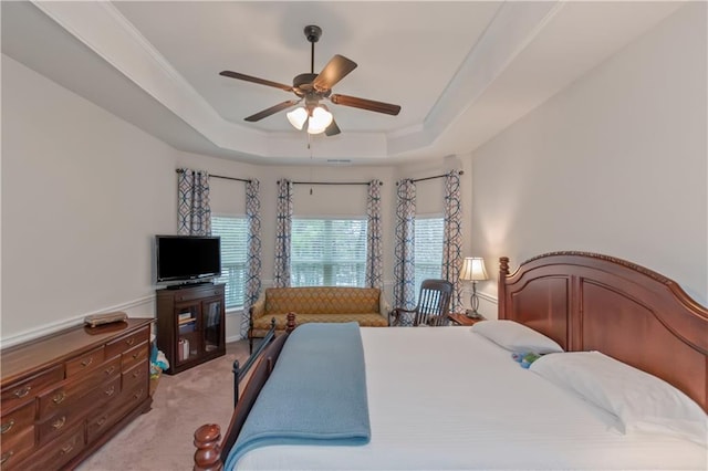 bedroom featuring a raised ceiling, crown molding, light carpet, and ceiling fan