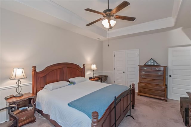 bedroom featuring crown molding, ceiling fan, a tray ceiling, light carpet, and a closet