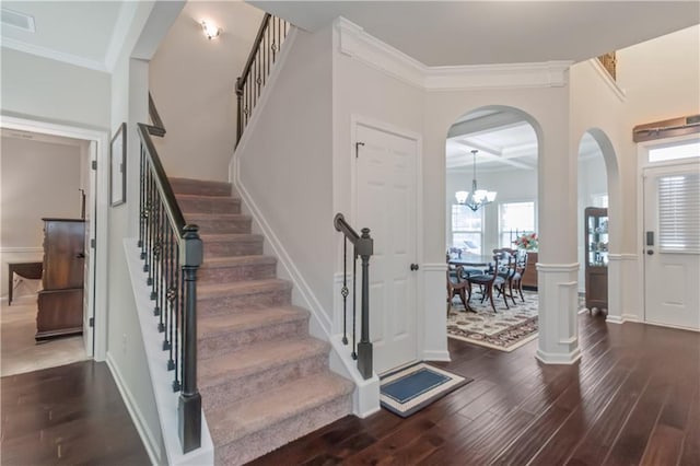 entrance foyer with a chandelier, dark hardwood / wood-style flooring, coffered ceiling, crown molding, and beam ceiling