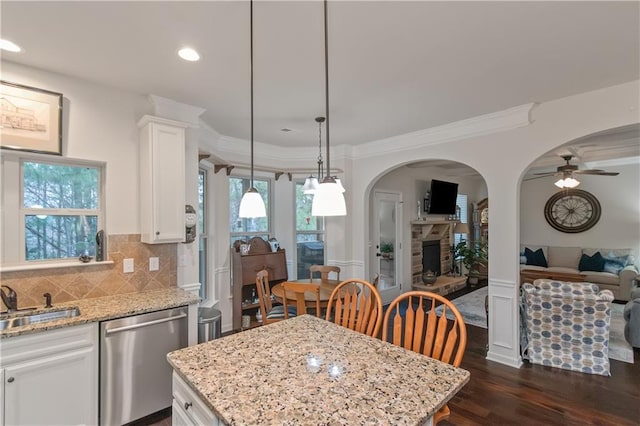 kitchen featuring sink, dishwasher, pendant lighting, light stone countertops, and white cabinets