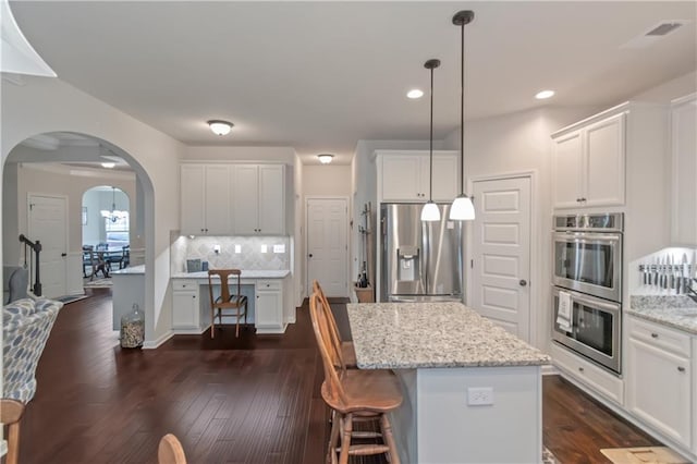 kitchen featuring light stone counters, stainless steel appliances, white cabinets, and a kitchen island