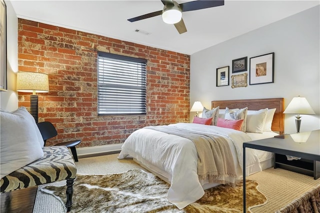 bedroom featuring ceiling fan and brick wall