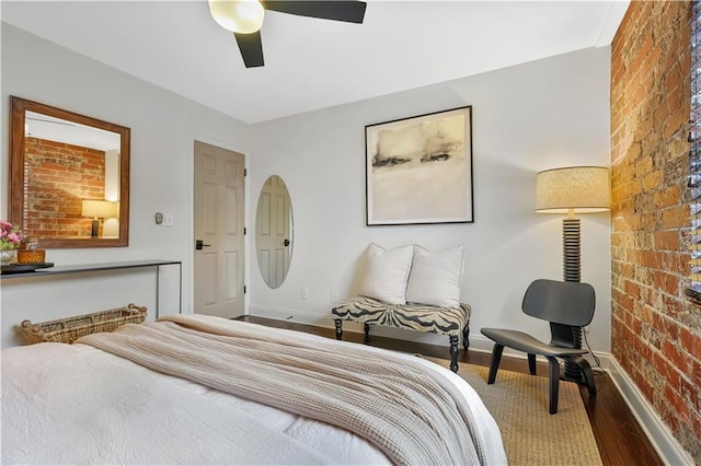 bedroom with wood-type flooring, brick wall, and ceiling fan