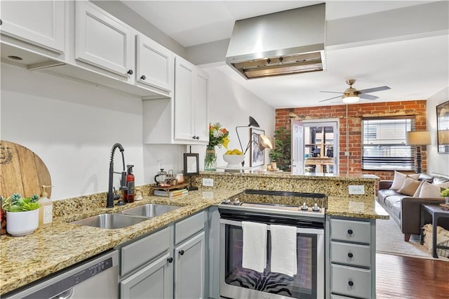 kitchen featuring sink, white cabinets, kitchen peninsula, stainless steel appliances, and wall chimney range hood