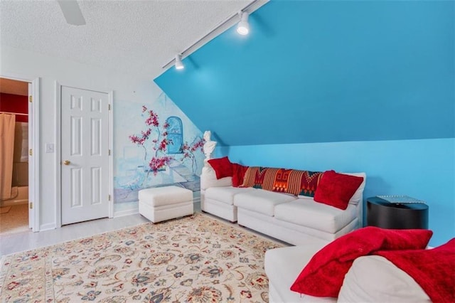 living room with lofted ceiling, hardwood / wood-style flooring, rail lighting, ceiling fan, and a textured ceiling