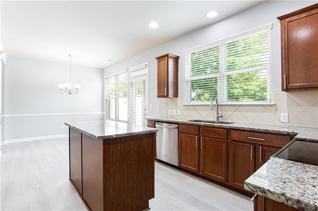 kitchen with decorative light fixtures, a kitchen island, stainless steel dishwasher, decorative backsplash, and sink