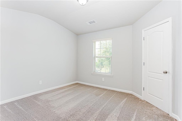 carpeted empty room featuring vaulted ceiling