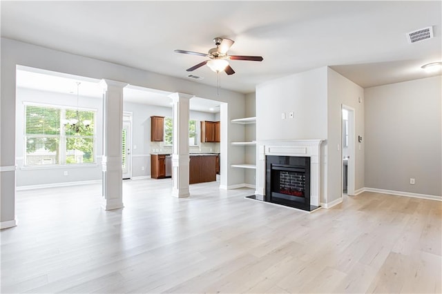 unfurnished living room featuring ceiling fan, built in shelves, light hardwood / wood-style flooring, and decorative columns