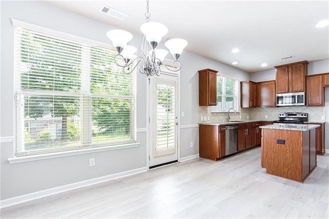 kitchen featuring pendant lighting, a center island, decorative backsplash, an inviting chandelier, and stainless steel appliances