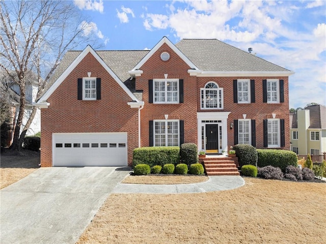 colonial inspired home featuring a garage, brick siding, driveway, and roof with shingles