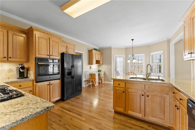 kitchen featuring ornamental molding, light wood-type flooring, black appliances, a chandelier, and a sink