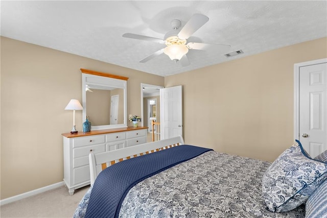 bedroom featuring light carpet, baseboards, visible vents, and a textured ceiling