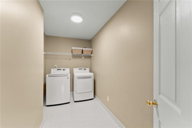 washroom with laundry area, separate washer and dryer, and baseboards