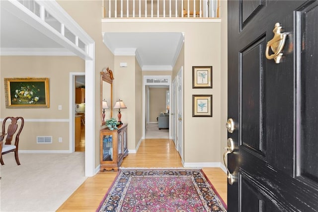 entryway featuring baseboards, light wood-style flooring, visible vents, and crown molding