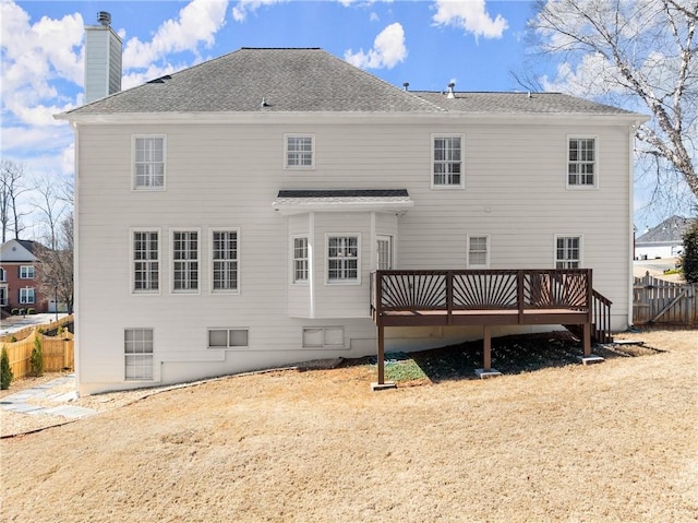 rear view of property with roof with shingles, a chimney, fence, and a wooden deck