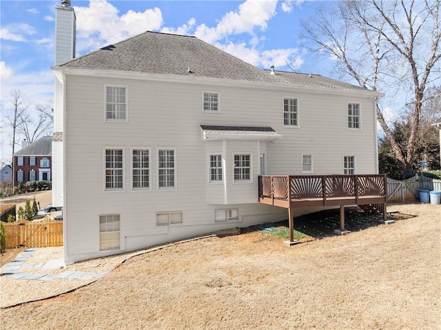 rear view of property with roof with shingles, a chimney, fence, and a wooden deck