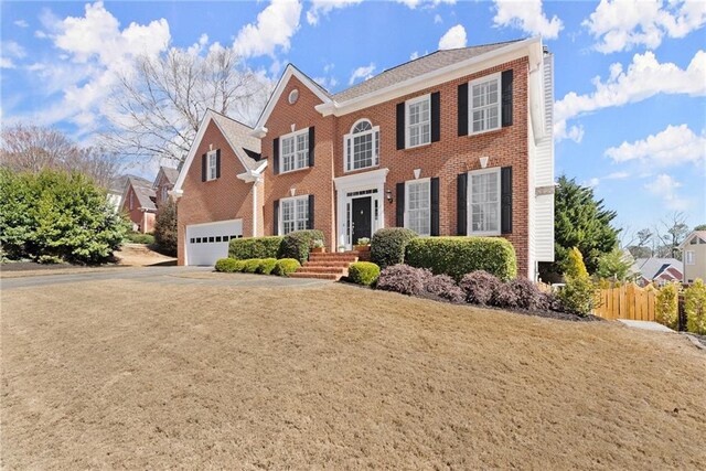 view of front facade featuring concrete driveway, brick siding, fence, and an attached garage