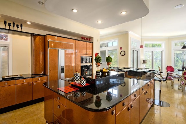 kitchen featuring a wealth of natural light, a center island, dark stone countertops, and paneled fridge