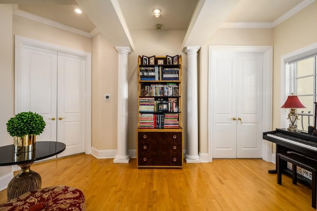 interior space with crown molding, light wood-type flooring, and decorative columns