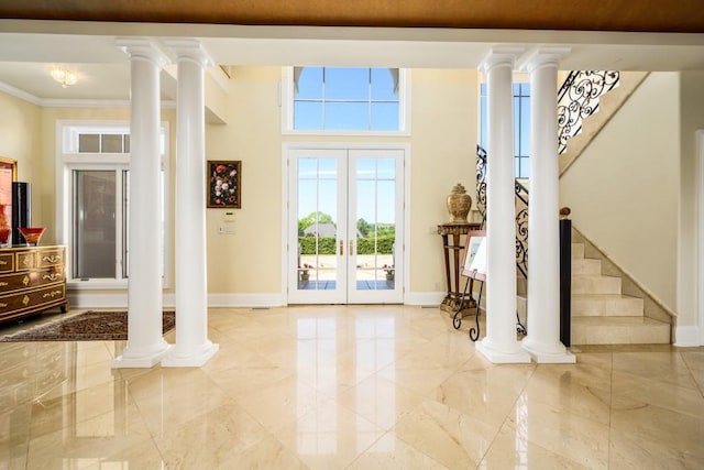 entryway with crown molding, a healthy amount of sunlight, and decorative columns