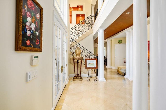 hall featuring a high ceiling and ornate columns