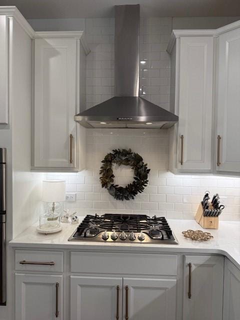 63 Aspen Way, Dallas, GA 30157 - kitchen featuring wall chimney range hood, stainless steel gas cooktop, backsplash, white cabinetry, and light countertops