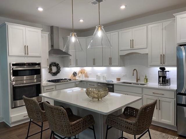 63 Aspen Way, Dallas, GA 30157 - kitchen featuring wall chimney exhaust hood, a sink, stainless steel appliances, a kitchen breakfast bar, and light countertops