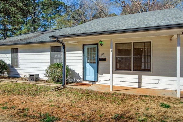 entrance to property with a lawn and roof with shingles