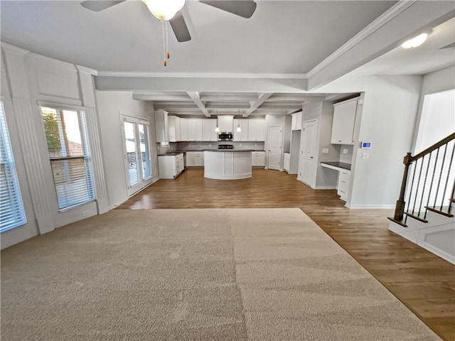 unfurnished living room with coffered ceiling, crown molding, ceiling fan, dark wood-type flooring, and beam ceiling