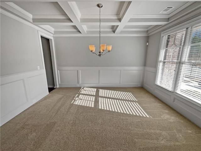 unfurnished dining area featuring beam ceiling, a healthy amount of sunlight, coffered ceiling, and an inviting chandelier