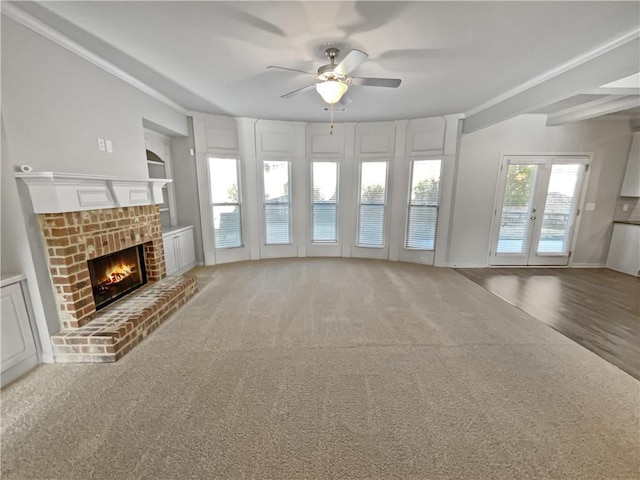 unfurnished living room with french doors, built in shelves, carpet floors, a fireplace, and ceiling fan