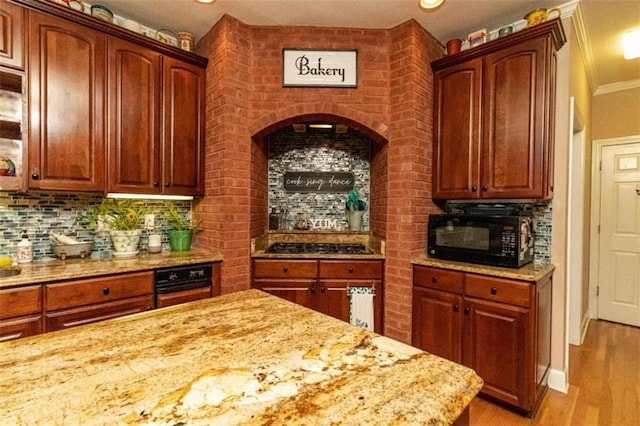 kitchen with decorative backsplash, stainless steel gas cooktop, light stone countertops, ornamental molding, and light hardwood / wood-style flooring