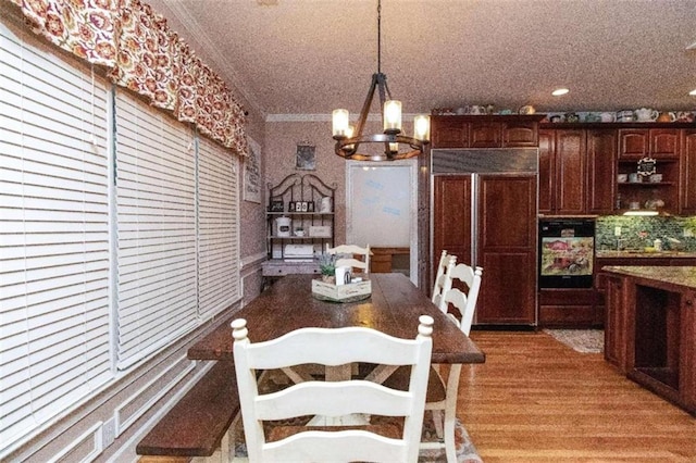 dining area featuring wood-type flooring, a notable chandelier, and crown molding