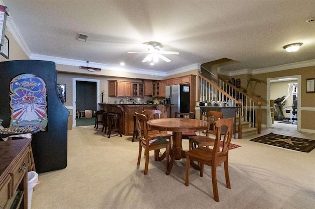 dining room with ceiling fan, light colored carpet, and ornamental molding