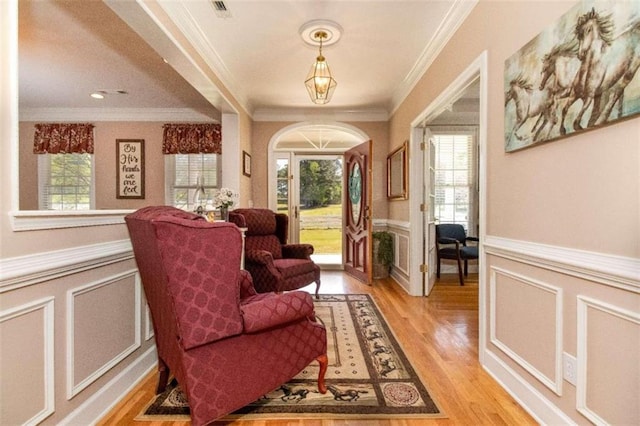 living area featuring ornamental molding and light hardwood / wood-style floors