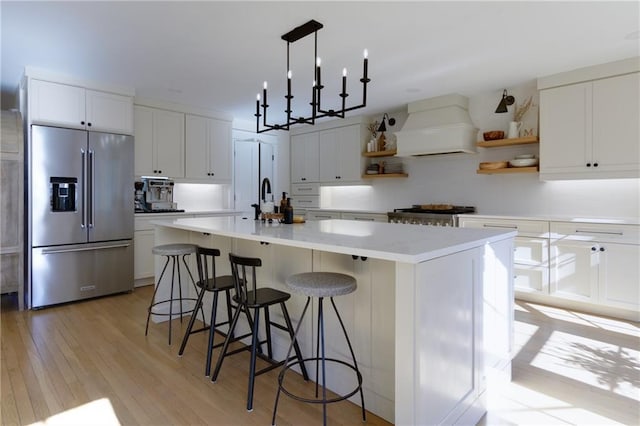 kitchen with a center island, open shelves, custom range hood, high quality fridge, and range