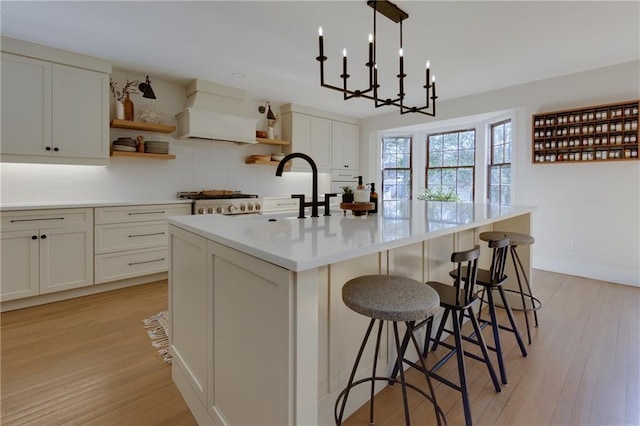 kitchen featuring open shelves, tasteful backsplash, custom exhaust hood, and light wood-style flooring